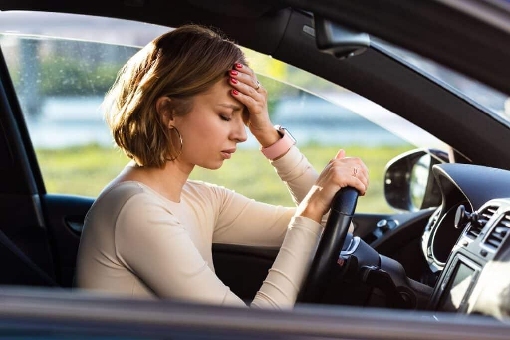 A driver pressing a hand to her forehead after a car accident